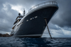 Large ocean-going motor cruiser at anchor, low angle from the water