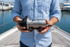 Savwinch Deck Wash Pump held on a boat deck with a marina in the background
