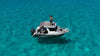 Aerial view of two people on a boat anchored in clear turquoise water