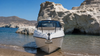 White boat anchored in clear shallows beside white rock cliffs
