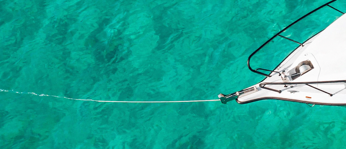 Aerial view of a Savwinch rope and chain rode running from a boat's bow roller into clear turquoise water