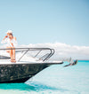 Woman seated on the bow of a boat with a stainless anchor over turquoise water